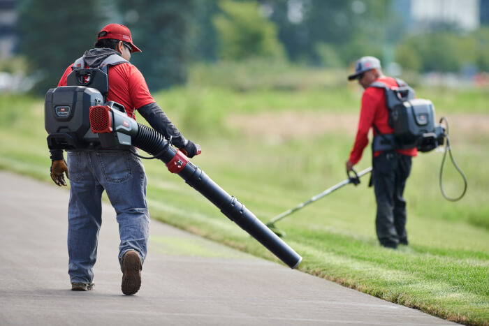 Técnicos com equipamentos manuais a bateria na manutenção de espaços verdes
